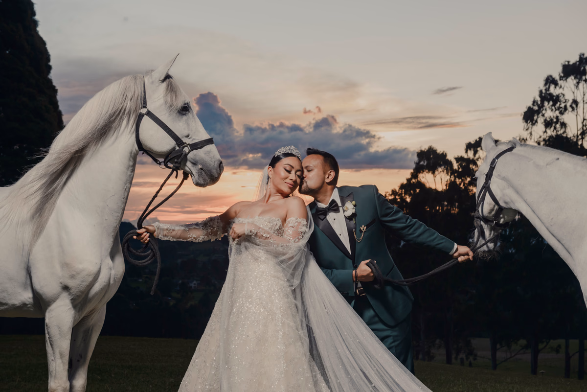 Pareja junto a caballos blancos al atardecer